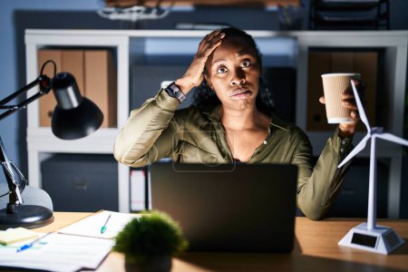Photo for African woman working using computer laptop at night worried and stressed about a problem with hand on forehead, nervous and anxious for crisis - Royalty Free Image