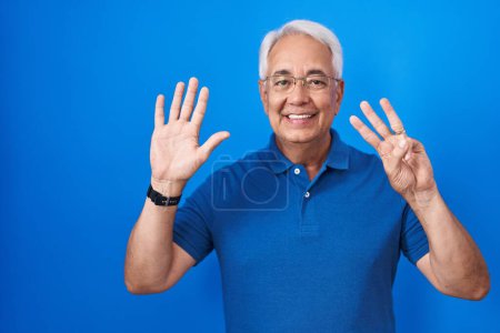 Photo for Middle age man with grey hair standing over blue background showing and pointing up with fingers number eight while smiling confident and happy. - Royalty Free Image