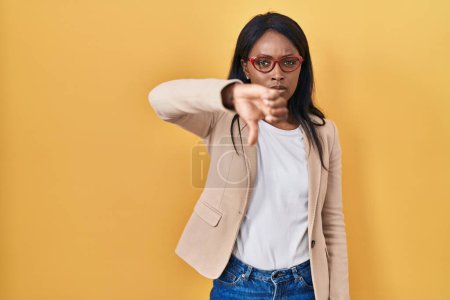 Téléchargez les photos : Jeune femme africaine portant des lunettes regardant malheureux et en colère montrant rejet et négatif avec les pouces vers le bas geste. mauvaise expression. - en image libre de droit