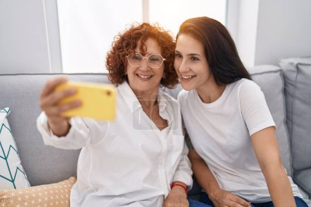 Foto de Dos mujeres madre e hija hacen selfie por teléfono inteligente en casa - Imagen libre de derechos