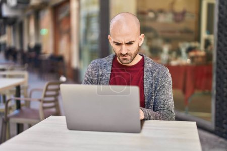 Téléchargez les photos : Jeune homme utilisant un ordinateur portable assis sur la table à la terrasse du café - en image libre de droit
