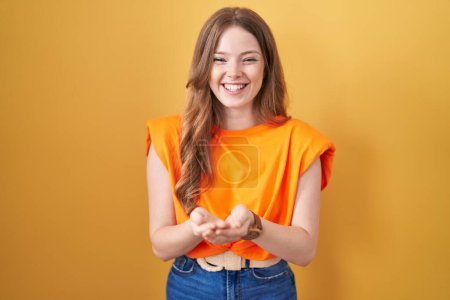 Photo for Caucasian woman standing over yellow background smiling with hands palms together receiving or giving gesture. hold and protection - Royalty Free Image