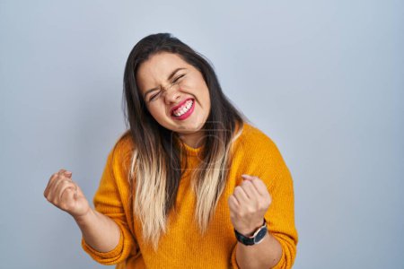 Photo for Young hispanic woman standing over isolated background very happy and excited doing winner gesture with arms raised, smiling and screaming for success. celebration concept. - Royalty Free Image