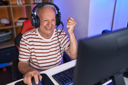 Photo for Middle age grey-haired man streamer playing video game with winner expression at gaming room - Royalty Free Image