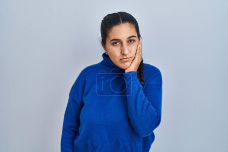 Foto de Mujer hispana joven de pie sobre un fondo aislado pensando que parece cansada y aburrida con problemas de depresión con los brazos cruzados. - Imagen libre de derechos