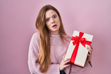Photo for Young caucasian woman holding gift clueless and confused expression. doubt concept. - Royalty Free Image