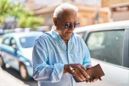 Foto de Hombre de pelo gris mayor sosteniendo billetera en la calle - Imagen libre de derechos