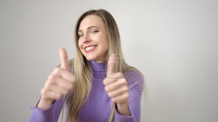 Téléchargez les photos : Jeune femme blonde souriante confiante faire ok signe avec les pouces vers le haut sur fond blanc isolé - en image libre de droit