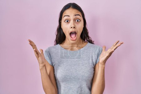 Photo for Young brazilian woman wearing casual t shirt over pink background celebrating crazy and amazed for success with arms raised and open eyes screaming excited. winner concept - Royalty Free Image