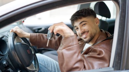 Foto de Hombre árabe joven sonriendo confiado sosteniendo la llave del coche nuevo en la calle - Imagen libre de derechos