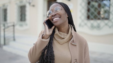 Foto de Mujer africana sonriendo hablando por teléfono en la calle - Imagen libre de derechos