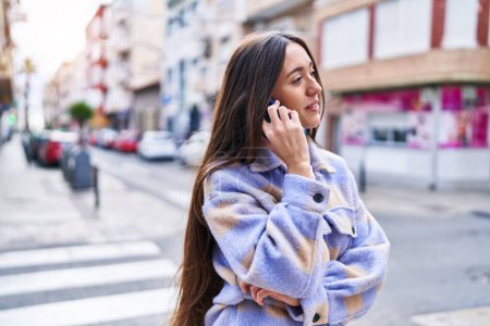 Téléchargez les photos : Jeune belle femme hispanique souriant confiant parler sur le smartphone à la rue - en image libre de droit