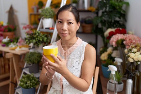 Photo for Young asian woman florist smiling confident drinking cup of coffee at flower shop - Royalty Free Image