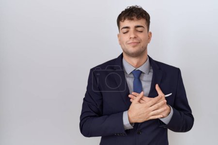 Photo for Young hispanic business man wearing suit and tie smiling with hands on chest with closed eyes and grateful gesture on face. health concept. - Royalty Free Image