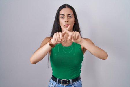 Photo for Young woman standing over isolated background rejection expression crossing fingers doing negative sign - Royalty Free Image