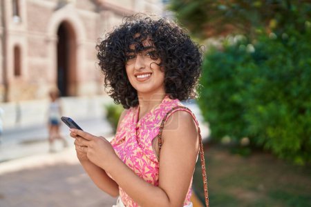 Photo for Young middle eastern woman smiling confident using smartphone at park - Royalty Free Image