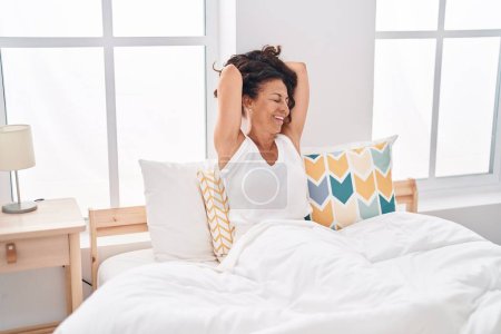 Photo for Middle age woman waking up stretching arms at bedroom - Royalty Free Image