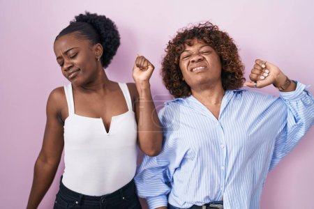 Photo for Two african women standing over pink background stretching back, tired and relaxed, sleepy and yawning for early morning - Royalty Free Image