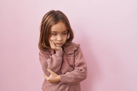Téléchargez les photos : Petite fille hispanique debout sur fond rose pensant fatigué et ennuyé avec des problèmes de dépression avec les bras croisés. - en image libre de droit