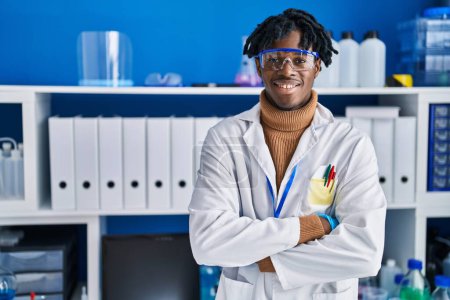 Téléchargez les photos : Homme scientifique afro-américain debout avec les bras croisés geste au laboratoire - en image libre de droit