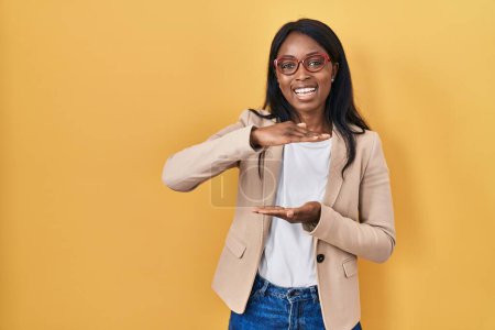 Photo for African young woman wearing glasses gesturing with hands showing big and large size sign, measure symbol. smiling looking at the camera. measuring concept. - Royalty Free Image
