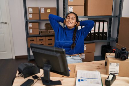 Téléchargez les photos : Jeune femme hispanique ecommerce travailleur d'affaires détendu avec les mains sur la tête au bureau - en image libre de droit