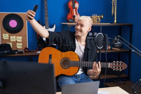 Photo for Young caucasian man musician playing classical guitar make selfie by smartphone at music studio - Royalty Free Image