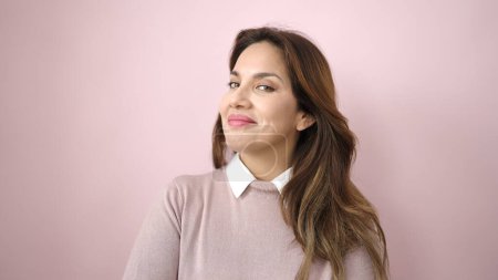 Foto de Joven hermosa mujer hispana sonriendo confiada de pie sobre un fondo rosa aislado - Imagen libre de derechos