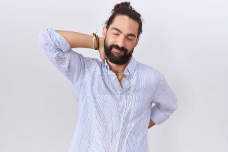 Téléchargez les photos : Homme hispanique avec barbe portant une chemise décontractée souffrant de douleurs au cou, touchant le cou avec la main, douleurs musculaires - en image libre de droit