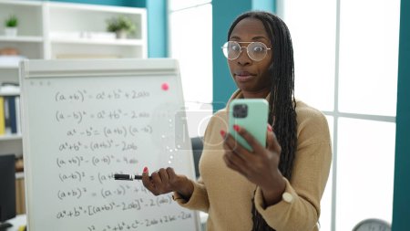 Foto de African woman recording teaching maths on magnetic board at library university - Imagen libre de derechos