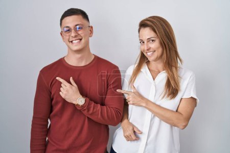 Photo for Mother and son standing together over isolated background cheerful with a smile on face pointing with hand and finger up to the side with happy and natural expression - Royalty Free Image
