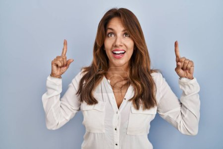 Photo for Hispanic woman standing over isolated background smiling amazed and surprised and pointing up with fingers and raised arms. - Royalty Free Image