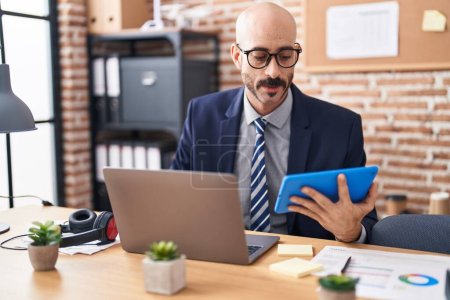 Téléchargez les photos : Young hispanic man business worker using laptop and touchpad at office - en image libre de droit