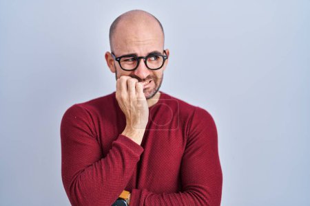 Photo for Young bald man with beard standing over white background wearing glasses looking stressed and nervous with hands on mouth biting nails. anxiety problem. - Royalty Free Image