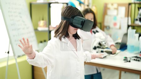 Foto de Adorable estudiante científica niñas utilizando gafas de realidad virtual en el aula de laboratorio - Imagen libre de derechos