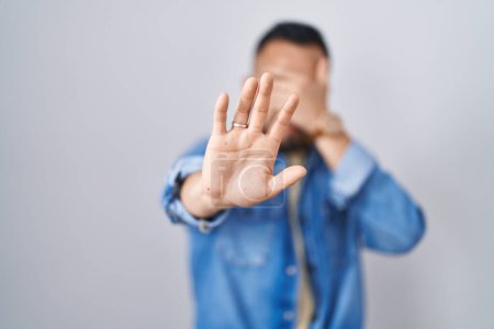 Photo for Young hispanic man standing over isolated background covering eyes with hands and doing stop gesture with sad and fear expression. embarrassed and negative concept. - Royalty Free Image