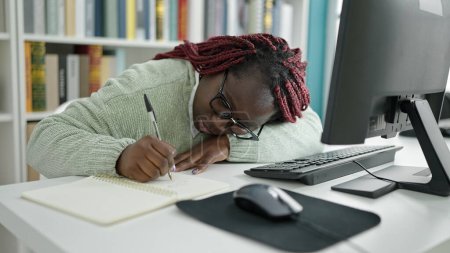 Photo for African woman with braided hair student writing notes tired at university library - Royalty Free Image