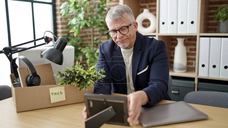 Photo for Middle age grey-haired man business worker dismissed putting things on cardboard box at office - Royalty Free Image