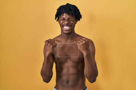 Photo for Young african man with dreadlocks standing shirtless excited for success with arms raised and eyes closed celebrating victory smiling. winner concept. - Royalty Free Image