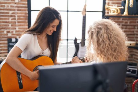Photo for Two women musicians having classical guitar lesson at music studio - Royalty Free Image