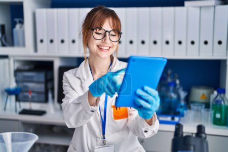 Téléchargez les photos : Young woman scientist smiling confident using touchpad at laboratory - en image libre de droit