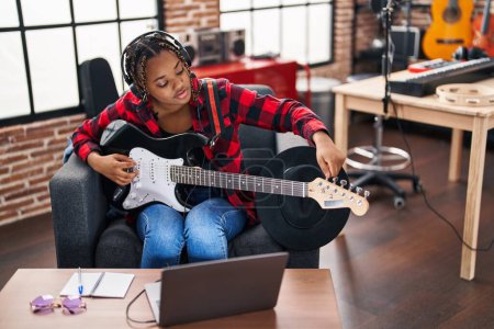 Foto de African american woman musician having online electrical guitar lesson at music studio - Imagen libre de derechos