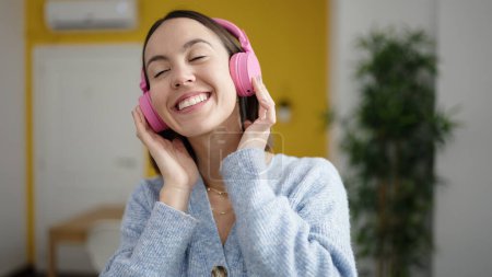 Photo for Young beautiful hispanic woman listening to music standing at home - Royalty Free Image