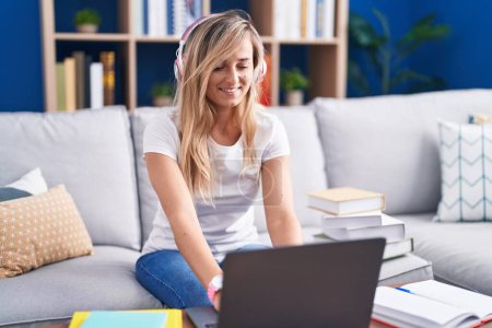 Young blonde woman studying using computer laptop at home with a happy and cool smile on face. lucky person.  Poster 653668988