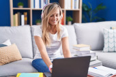 Young blonde woman studying using computer laptop at home with a happy and cool smile on face. lucky person.  Poster #653668988