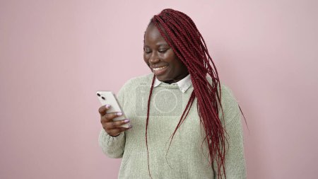Photo for African woman with braided hair using smartphone over isolated pink background - Royalty Free Image