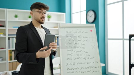 Téléchargez les photos : Jeune homme arabe enseignant les mathématiques leçon à l'aide de pavé tactile à l'université salle de classe - en image libre de droit