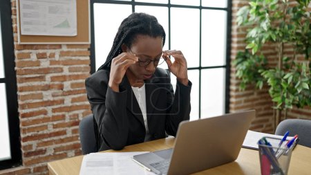 Foto de Trabajadora de negocios afroamericana estresada usando laptop en oficina - Imagen libre de derechos