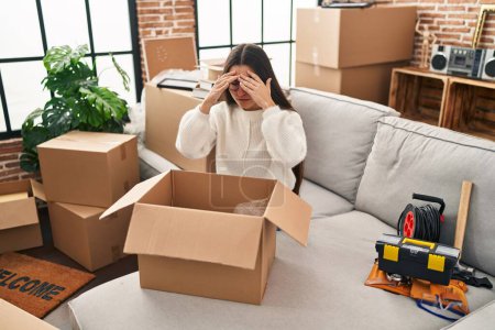 Photo for Young hispanic woman worried unpacking cardboard box at new home - Royalty Free Image