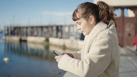 Foto de Mujer joven caucásica usando teléfono inteligente en la playa - Imagen libre de derechos